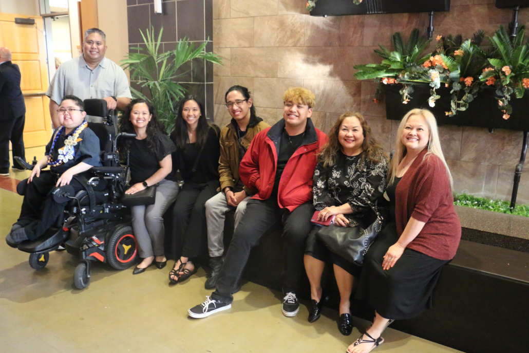 Family of seven poses with 8th grade male graduate in wheelchair at promotion ceremony