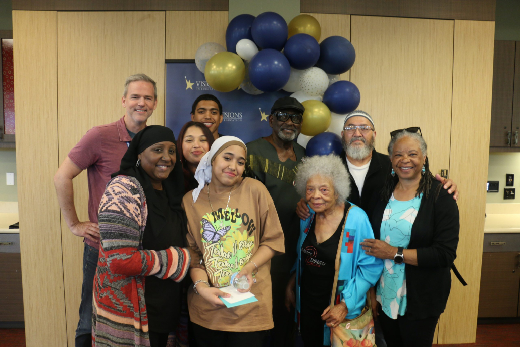 Family of eight poses in front of balloons with male teacher at 8th grade promotion
