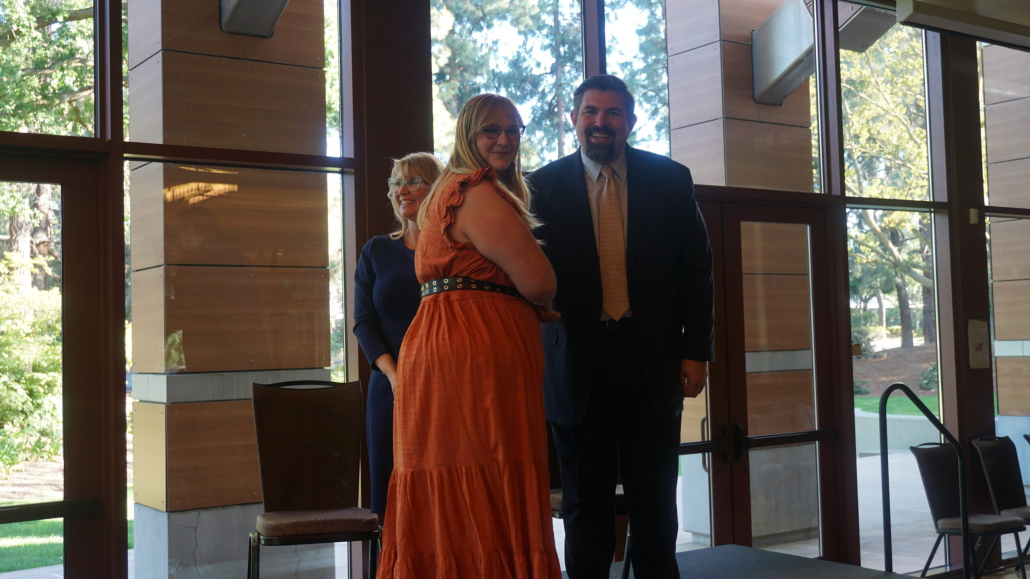 Chief Academic Officer Micah, shakes hand with female 8th grade graduate in orange dress on stage