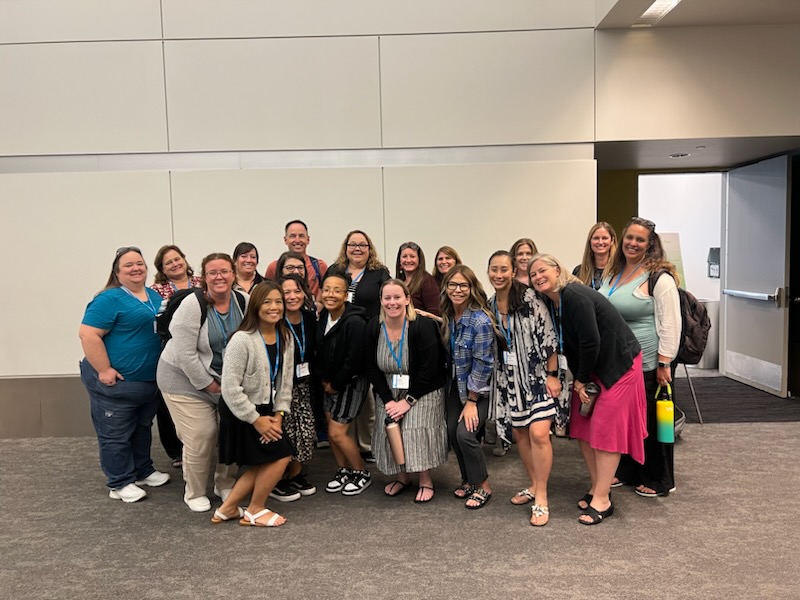 A large group of Visions staff gathers in the hallway at Safe Credit Union Convention Center and smiles for a photo.