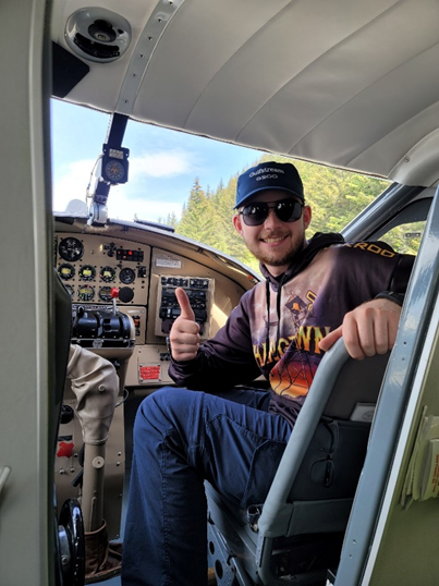 Sites 1 In a navy cap, black sunglasses and multi-colored sweatshirt, Hunter sits in the cockpit of a plane and gives a "thumbs up" to the camera.