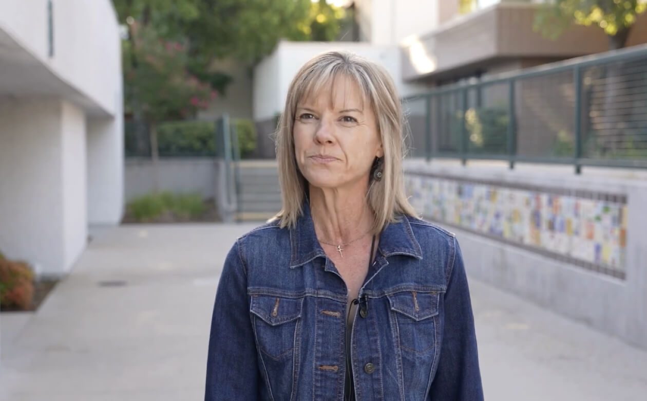 MIndi poses in front of a building, representing the commitment to student support and development.