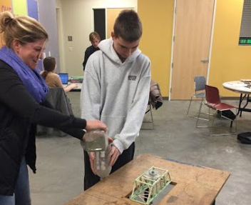 Image of student and teacher testing toothpick bridge with weight
