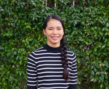 Bailey, female student stands in front of ivy covered wall