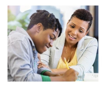 African American male student smiles while doing school work with teacher