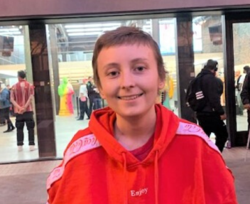 Independent study high school student, Talon B., smiles at the camera in a red sweatshirt