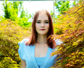 Female young adult smiles at camera in senior photo; graduating from online high school