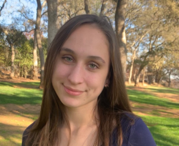 High school graduate smiles at the camera in a park