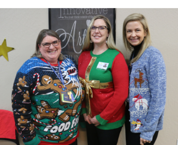 Loretta, Jessica and Kim stand together and pose for a photo wearing Christmas sweaters.