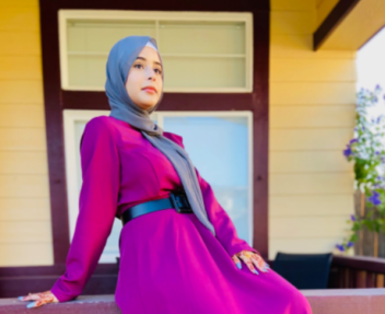 Female high school student in gray hijab sits on railing