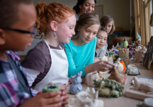 Teacher and group of home school students shaping clay figurines in art class