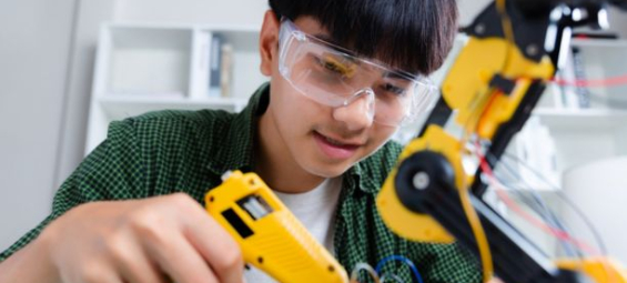 Asian teenager doing robot arm homework project at home, technology of robotics programing and STEM education