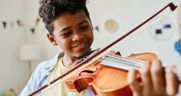 Smiling boy learning to play the violin