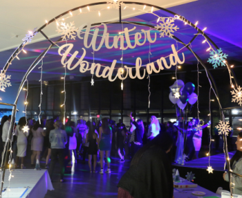 Arch with snowflakes and lights over the entrance to a community center room with a winter wonderland sign on it.