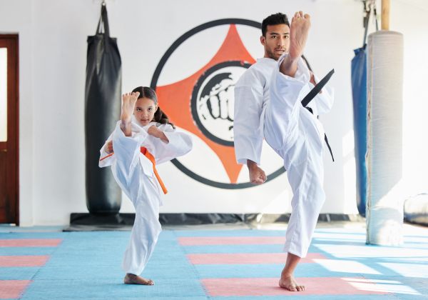 Shot of a young man and little girl practicing karate in a studio