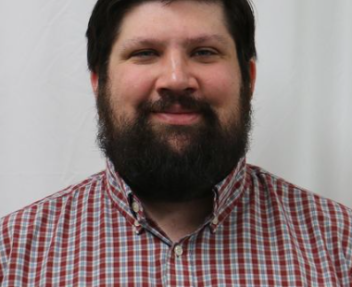 Michael Miller (staff member) in a red plaid shirt smiles for a staff photo.