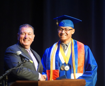 Male Superintendent poses with Filipino male graduate on staff at graduation